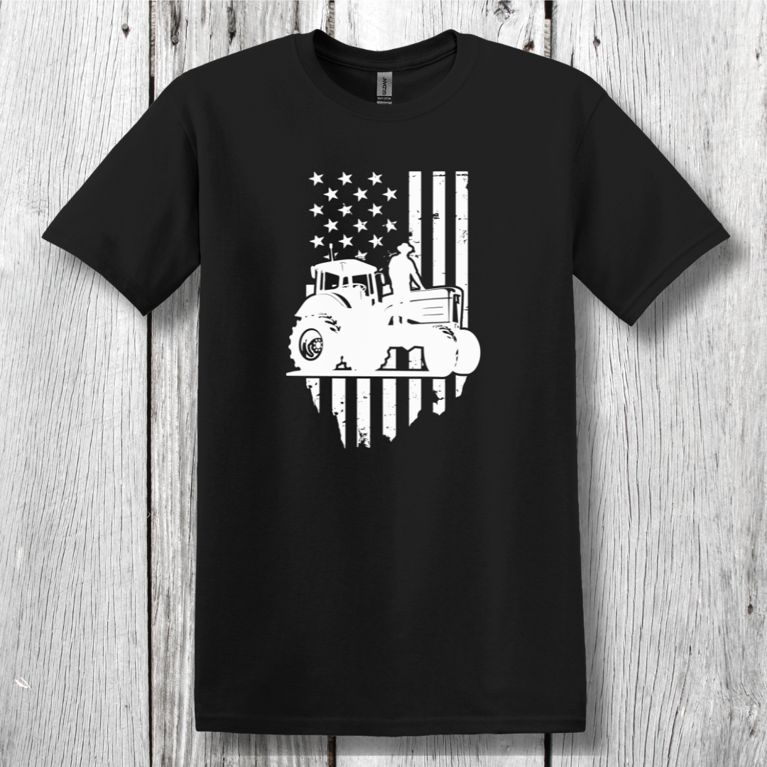 Black t-shirt with a white graphic of a tractor and American flag on a wooden surface