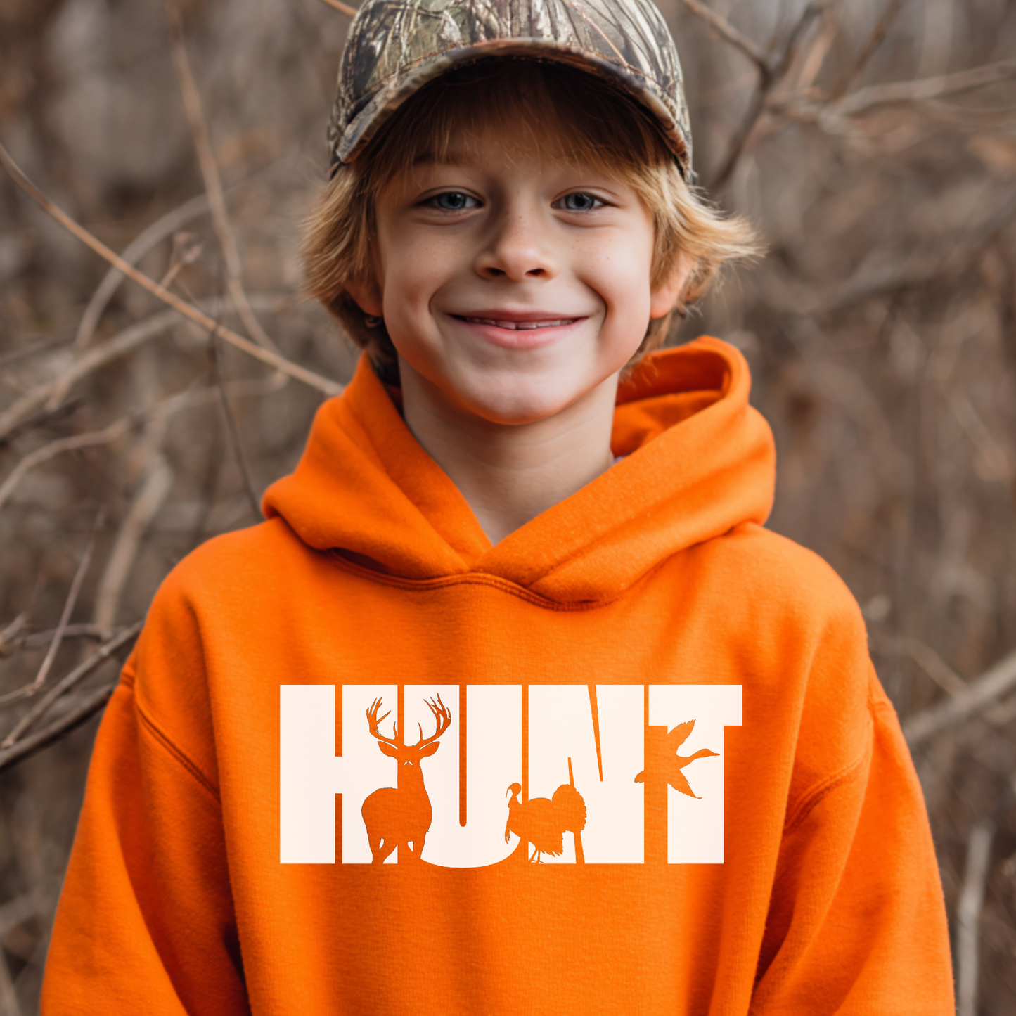 Child wearing an orange hoodie with 'HUNT' and animal graphics, standing in a natural setting.