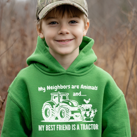Child wearing a green hoodie with a tractor graphic and text, standing outdoors.