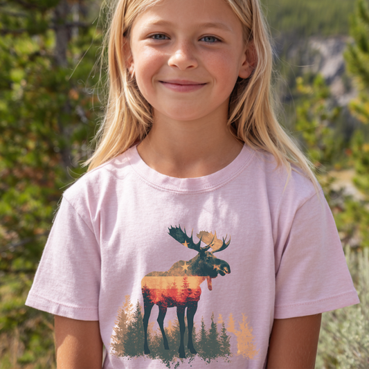 Young girl wearing a pink t-shirt with a moose graphic in a natural setting