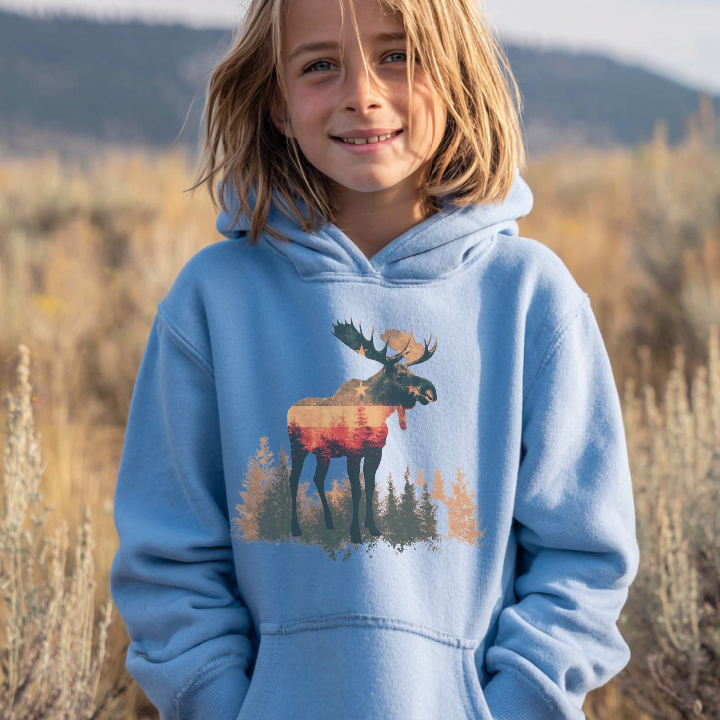 Child wearing a blue hoodie with a moose design in a natural setting