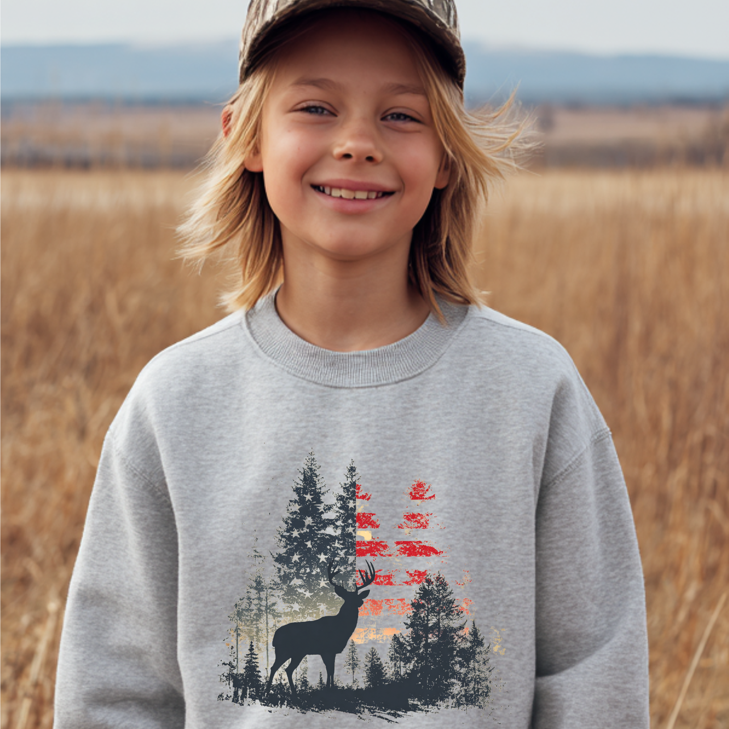 Child wearing a gray sweatshirt with a nature-themed design in a field