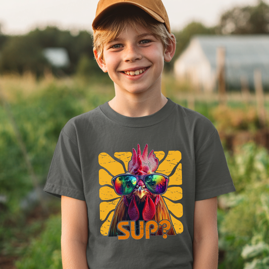 Child wearing a t-shirt with a rooster graphic and 'SUP?' text in a garden setting