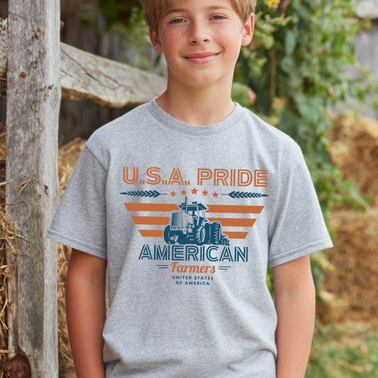 Child wearing a gray t-shirt with 'U.S.A. Pride American Farmers' design outdoors.