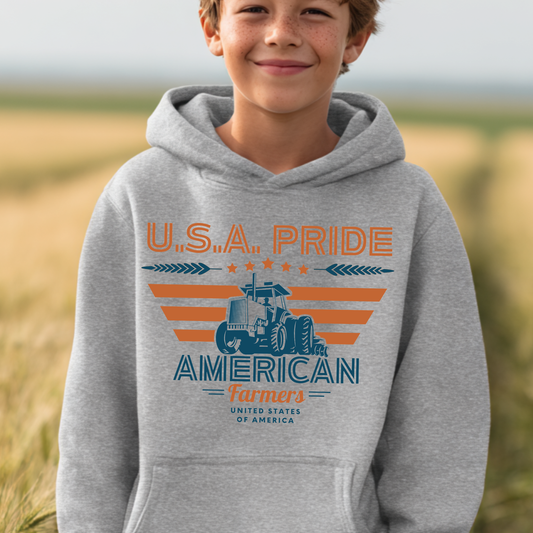 Child wearing a gray hoodie with 'U.S.A. Pride American Farmers' design in a field.