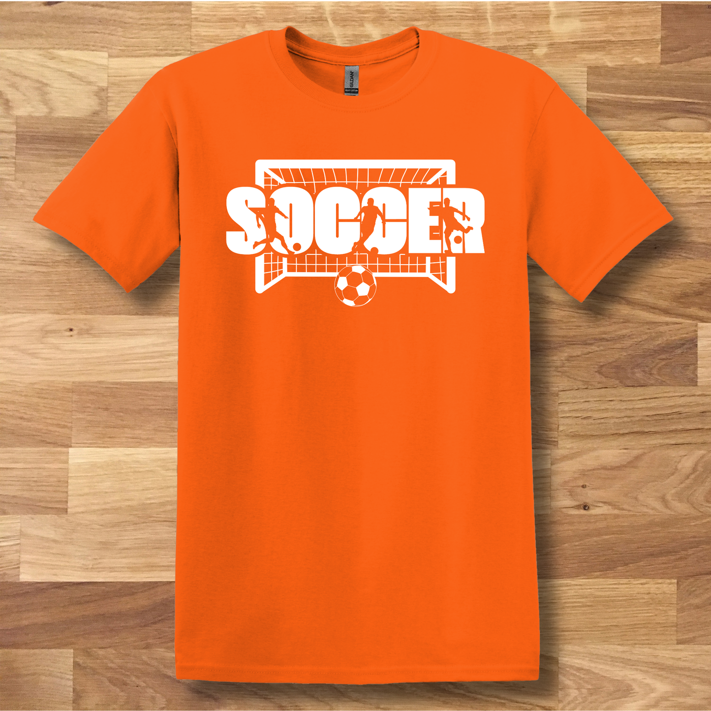 Orange t-shirt with 'SOCCER' graphic on a wooden surface