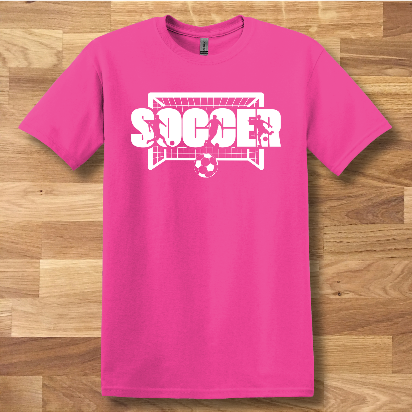Pink t-shirt with 'SOCCER' graphic on a wooden floor