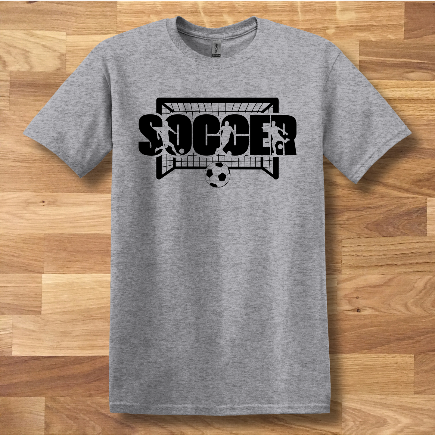Gray t-shirt with soccer graphic design on a wooden floor