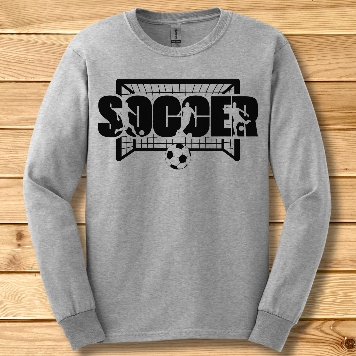 Gray long-sleeve shirt with soccer graphic on a wooden background