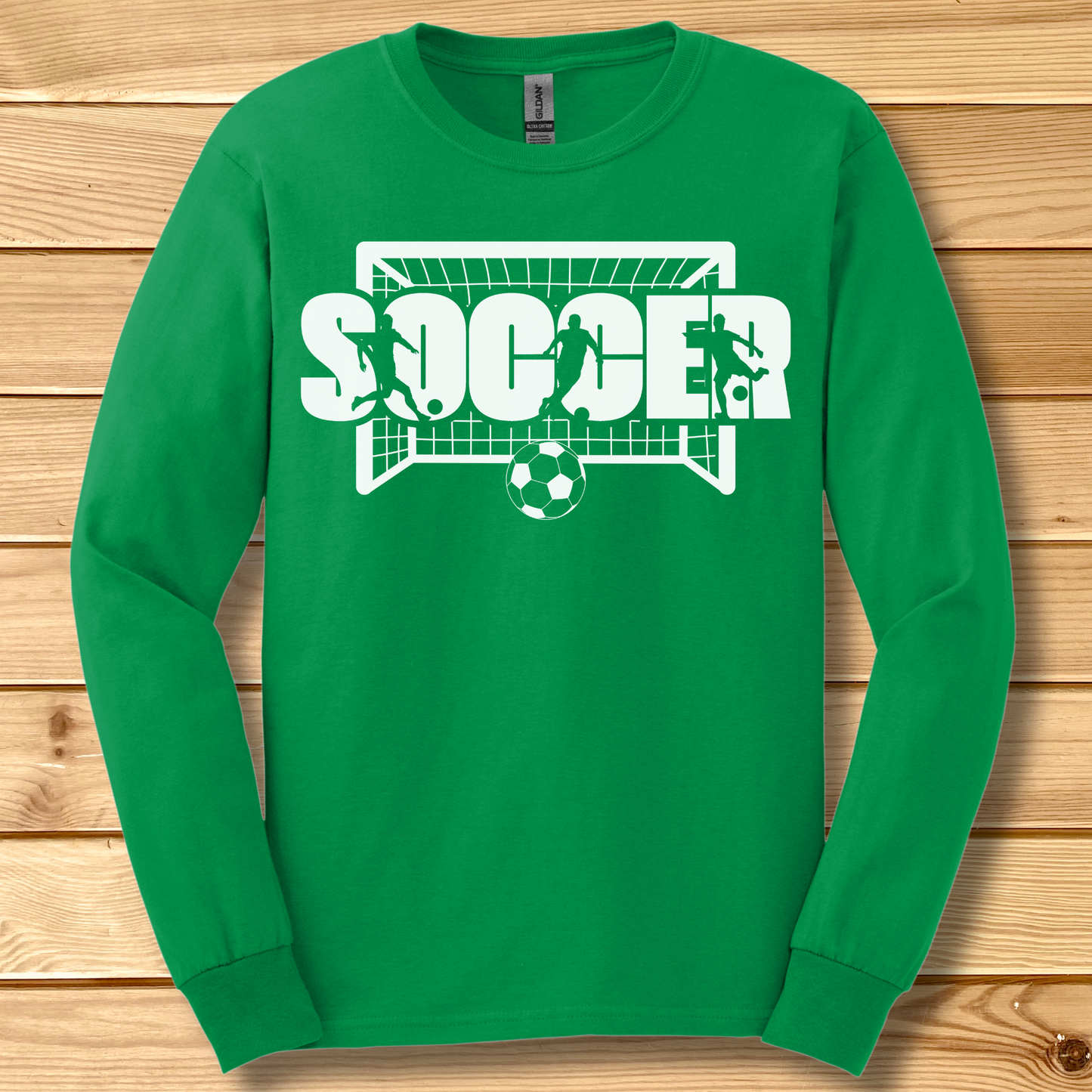 Green long-sleeve shirt with 'SOCCER' graphic on a wooden background