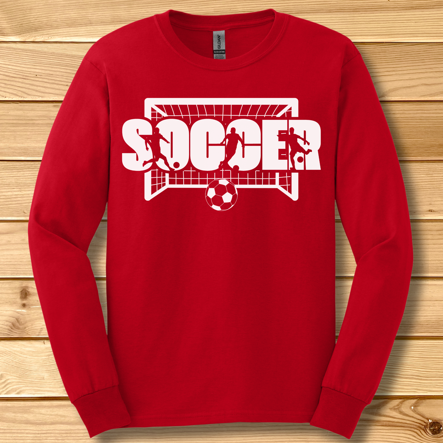 Red long-sleeve shirt with 'SOCCER' graphic on a wooden background
