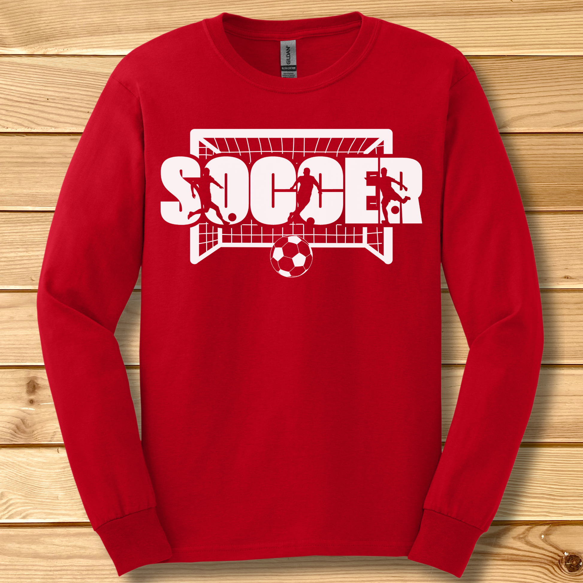 Red long-sleeve shirt with 'SOCCER' graphic on a wooden background