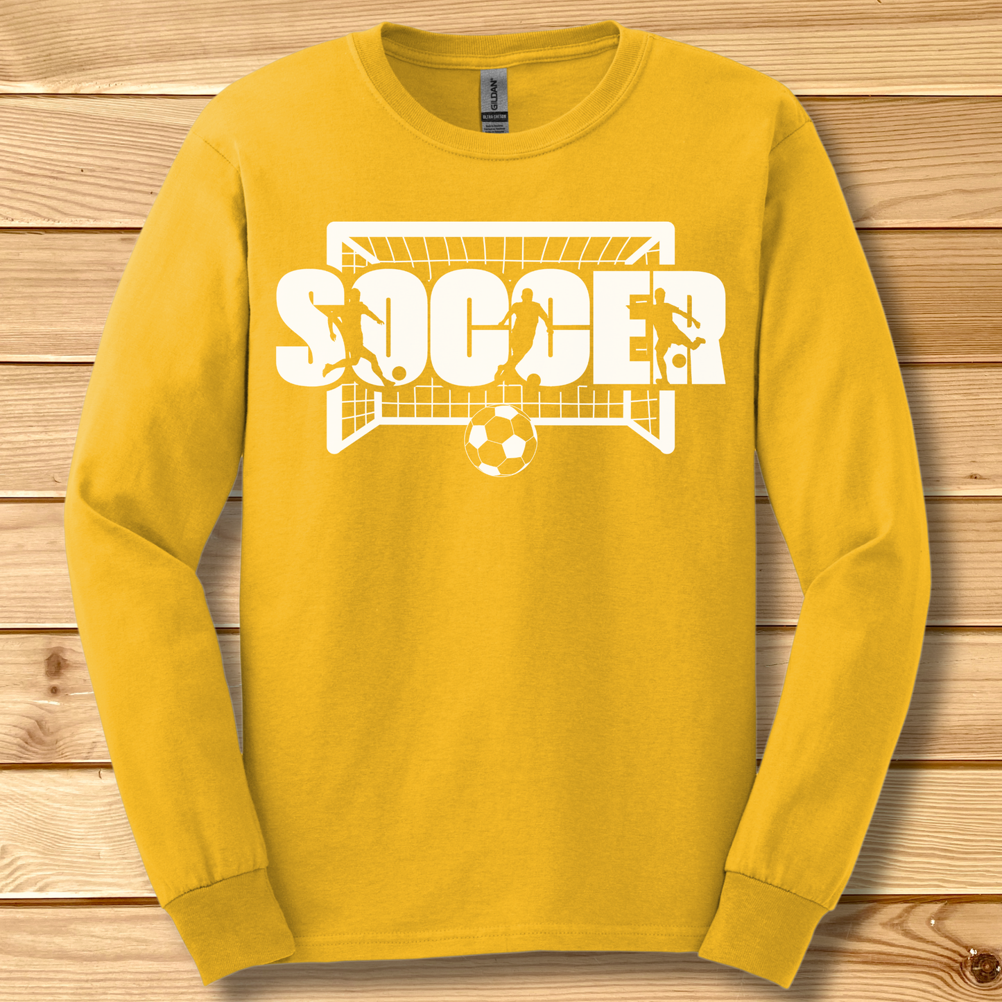 Yellow long-sleeve shirt with 'SOCCER' graphic on a wooden background
