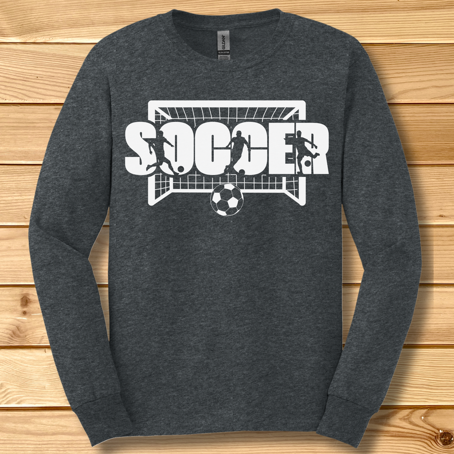 Dark gray long-sleeve shirt with 'SOCCER' graphic on a wooden surface
