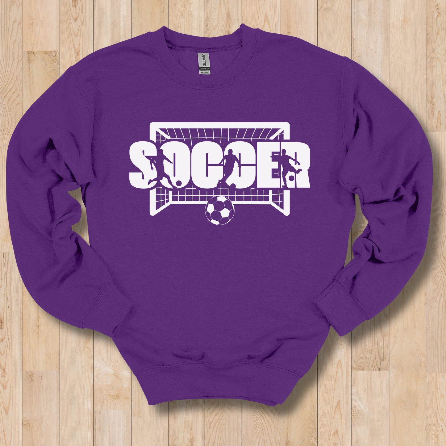 Purple sweatshirt with 'SOCCER' graphic on a wooden floor