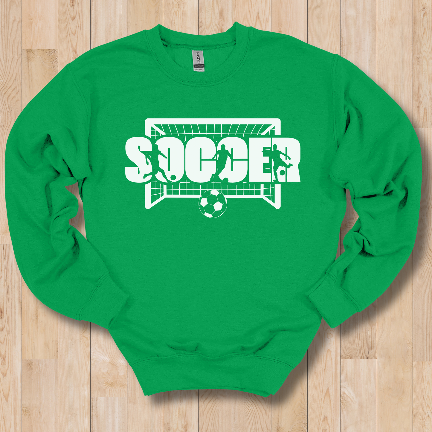 Green long-sleeve shirt with soccer graphic on a wooden floor