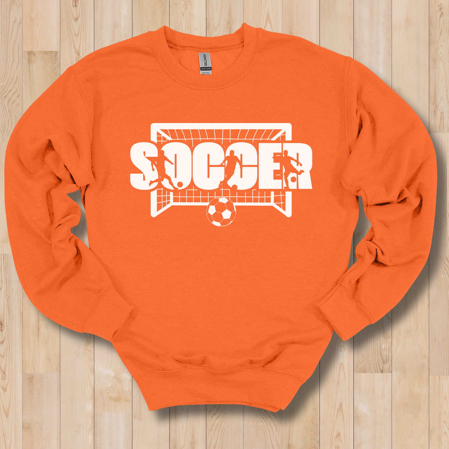 Orange sweatshirt with 'SOCCER' graphic on a wooden surface