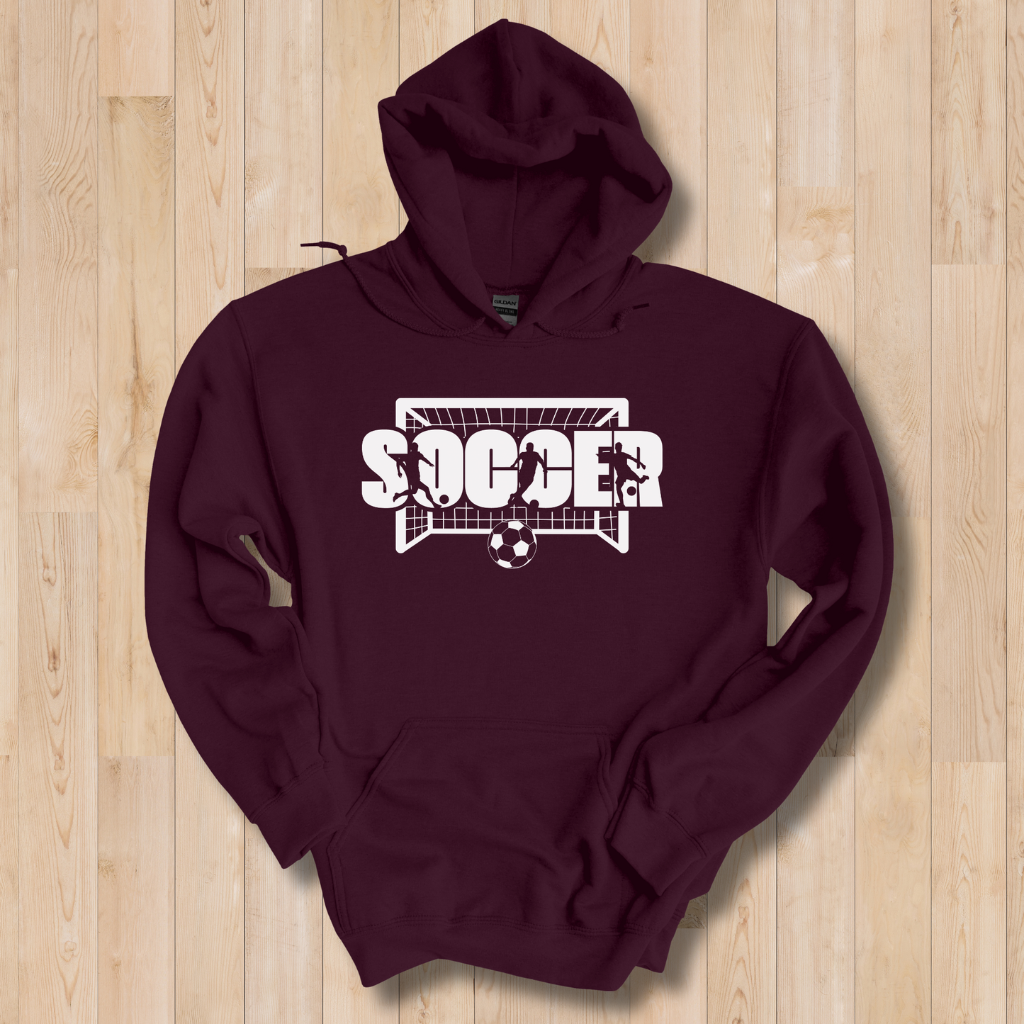 Maroon hoodie with 'Soccer' graphic on a wooden surface