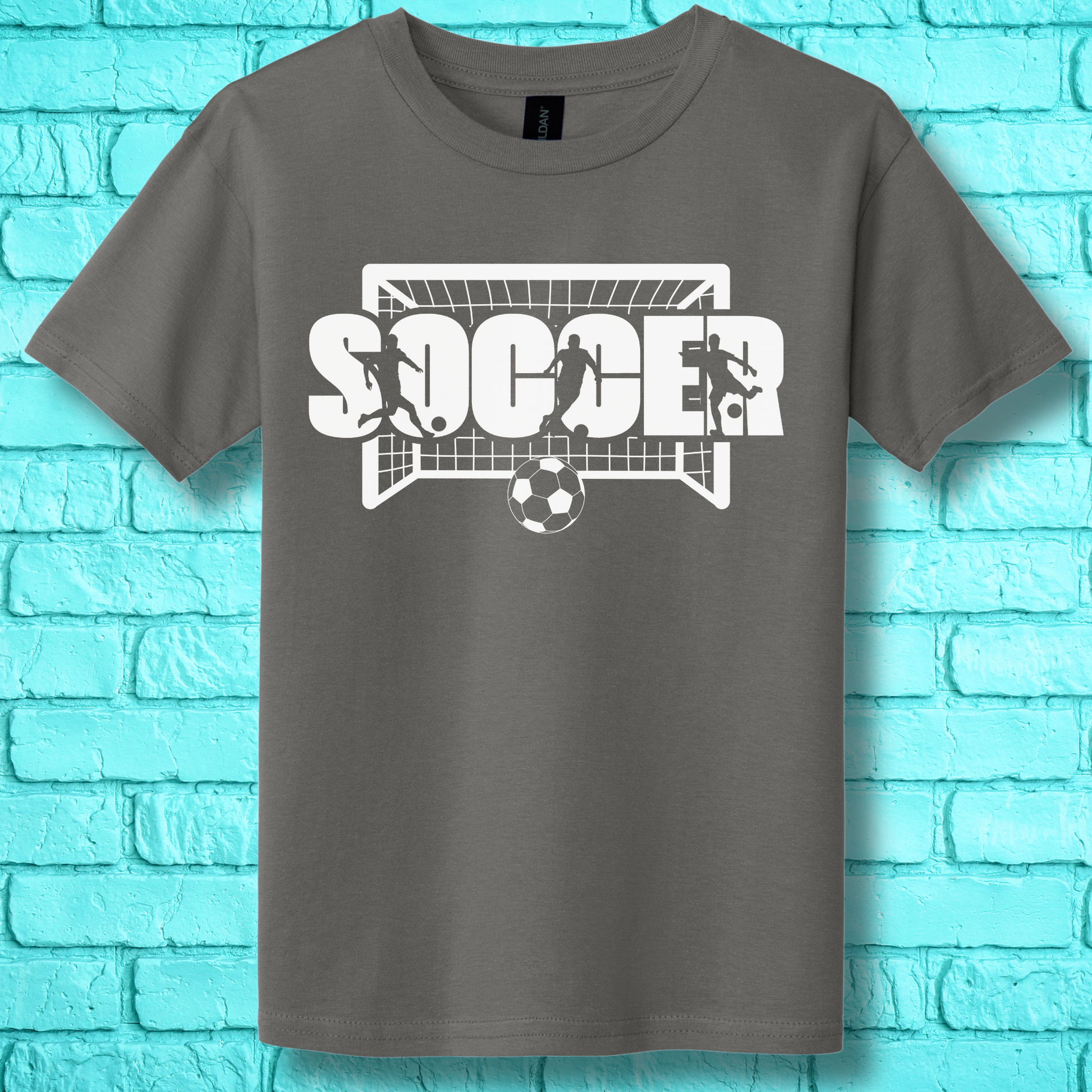 Gray t-shirt with soccer graphic design on a turquoise brick wall background