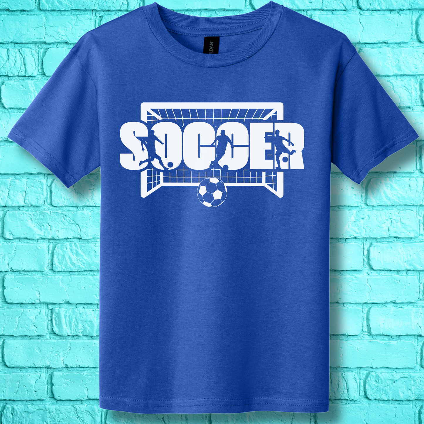 Blue t-shirt with 'SOCCER' graphic on a turquoise brick wall background
