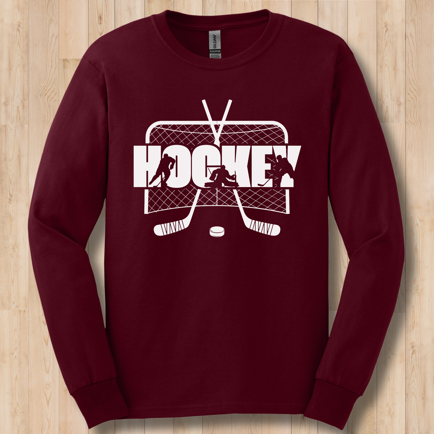 Maroon long-sleeve shirt with white hockey graphic on a wooden surface
