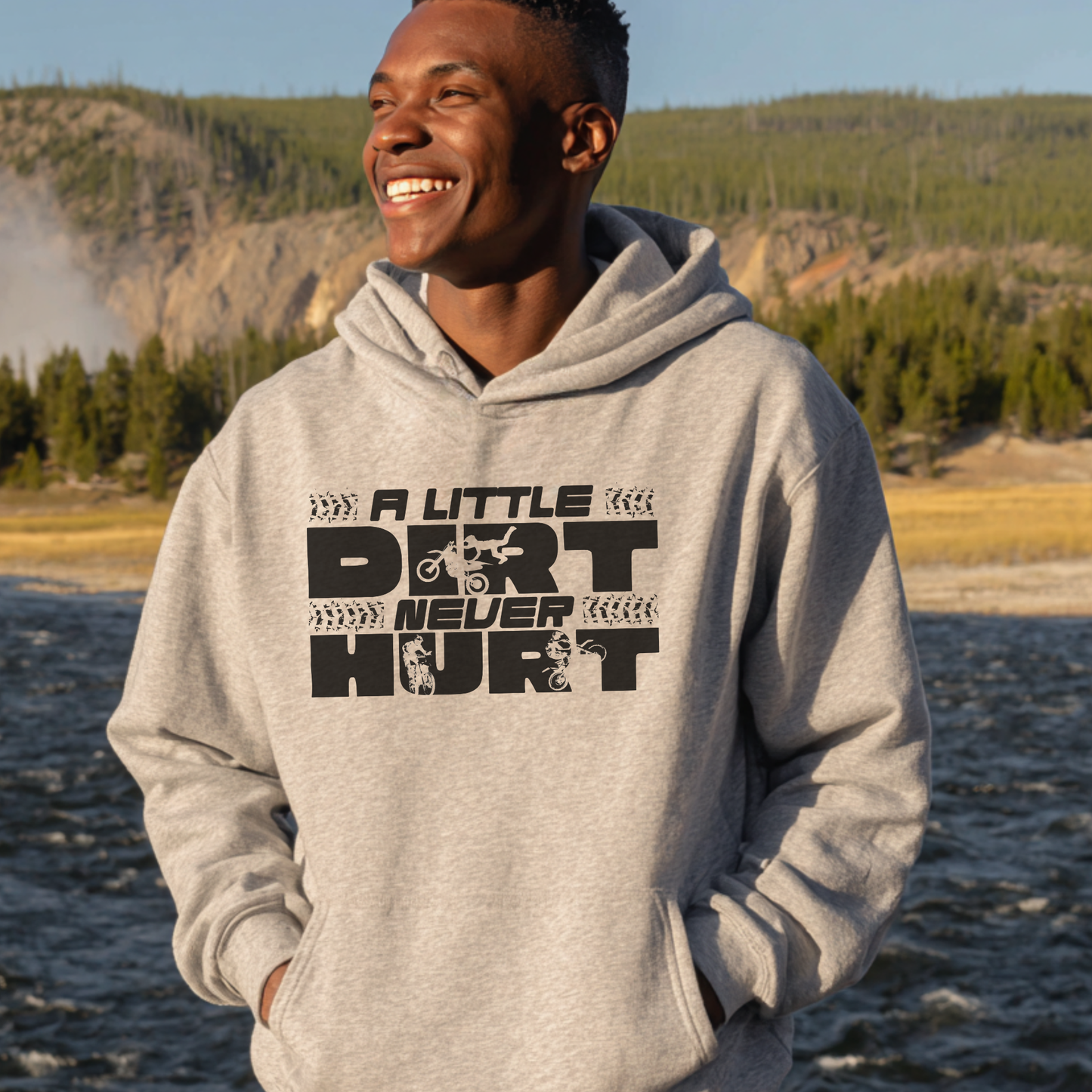 Person wearing a gray hoodie with 'A Little Dirt Never Hurt' text in a natural setting