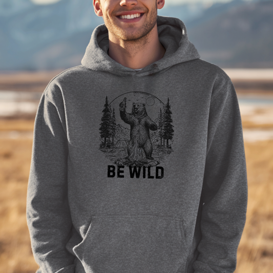 Person wearing a gray hoodie with a bear graphic and 'Be Wild' text in a natural setting