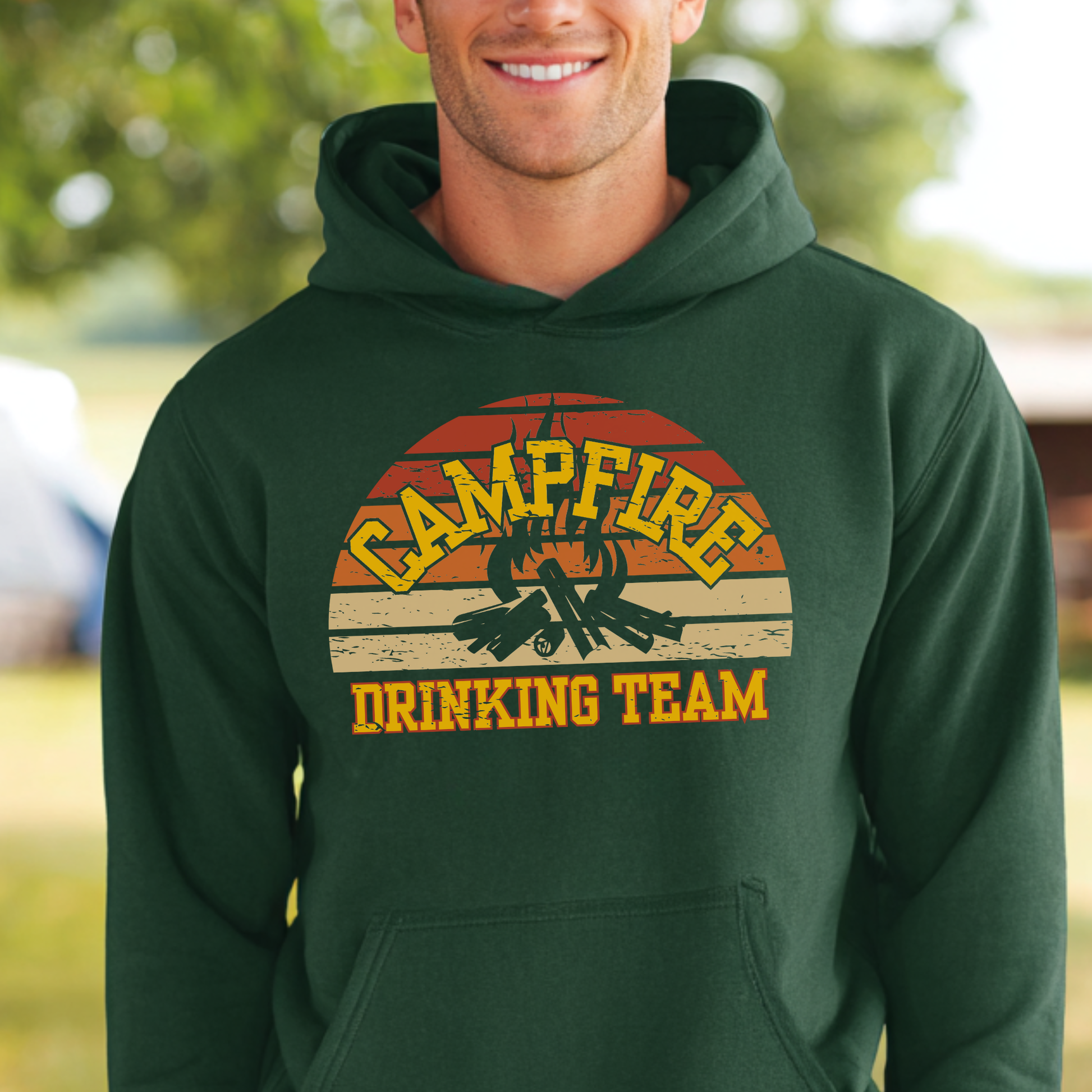 Person wearing a green hoodie with 'Campfire Drinking Team' design outdoors.