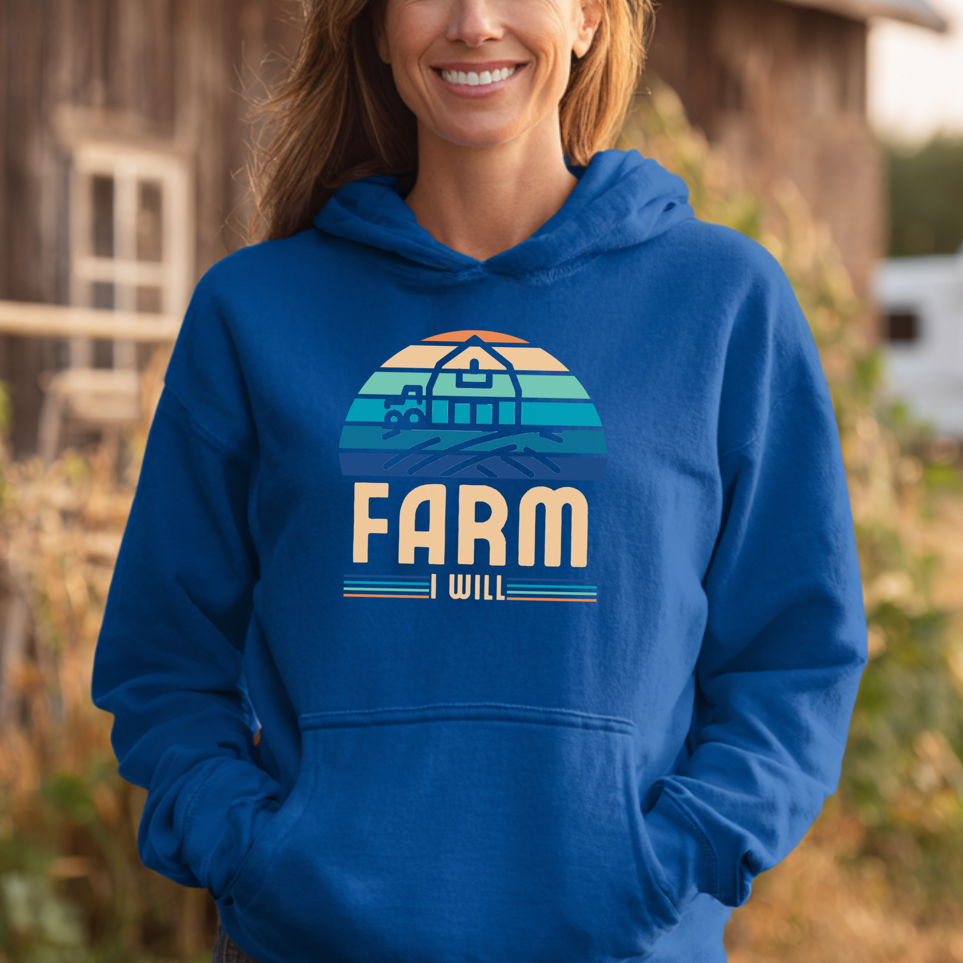Person wearing a blue hoodie with 'Farm I Will' design in a rural setting