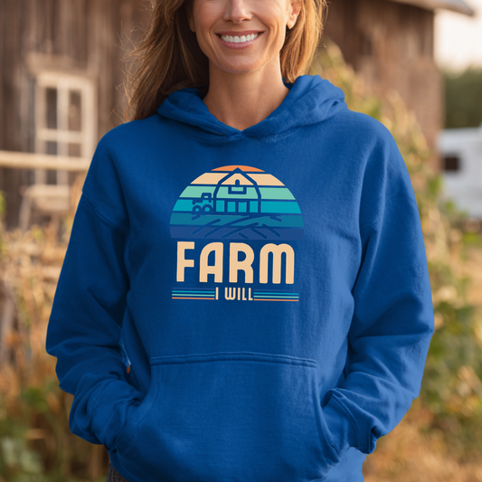 Person wearing a blue hoodie with 'Farm I Will' design in a rural setting