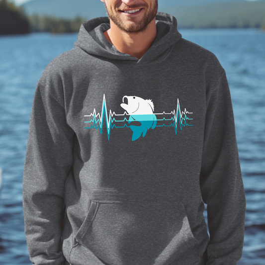Person wearing a gray hoodie with a fish and heartbeat design, standing by a body of water.