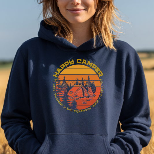 Person wearing a navy blue hoodie with 'Happy Camper' graphic design outdoors.