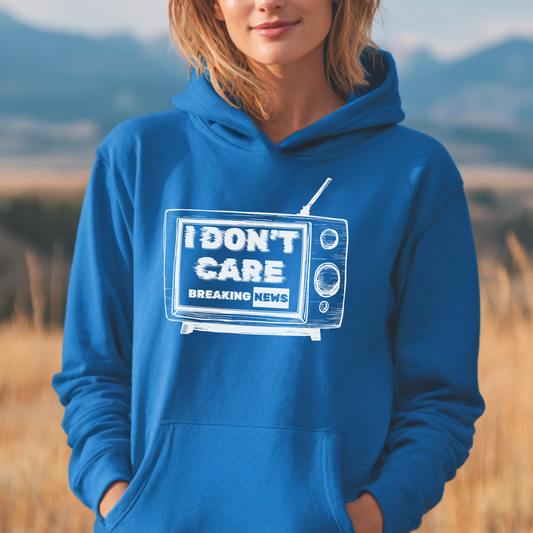 Person wearing a blue hoodie with a graphic design in a field with mountains in the background