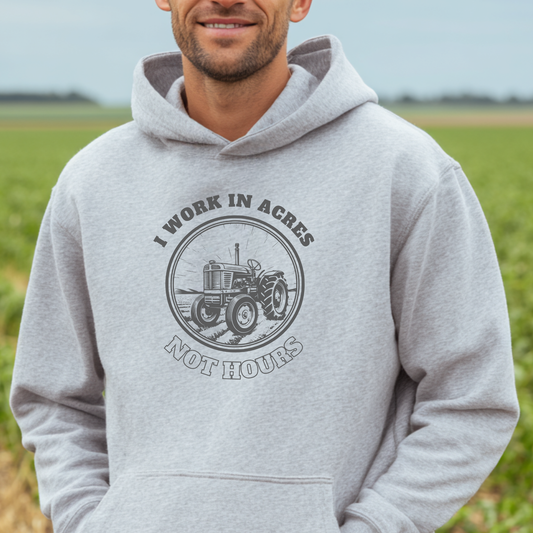 Person wearing a gray hoodie with a tractor graphic and text in a field