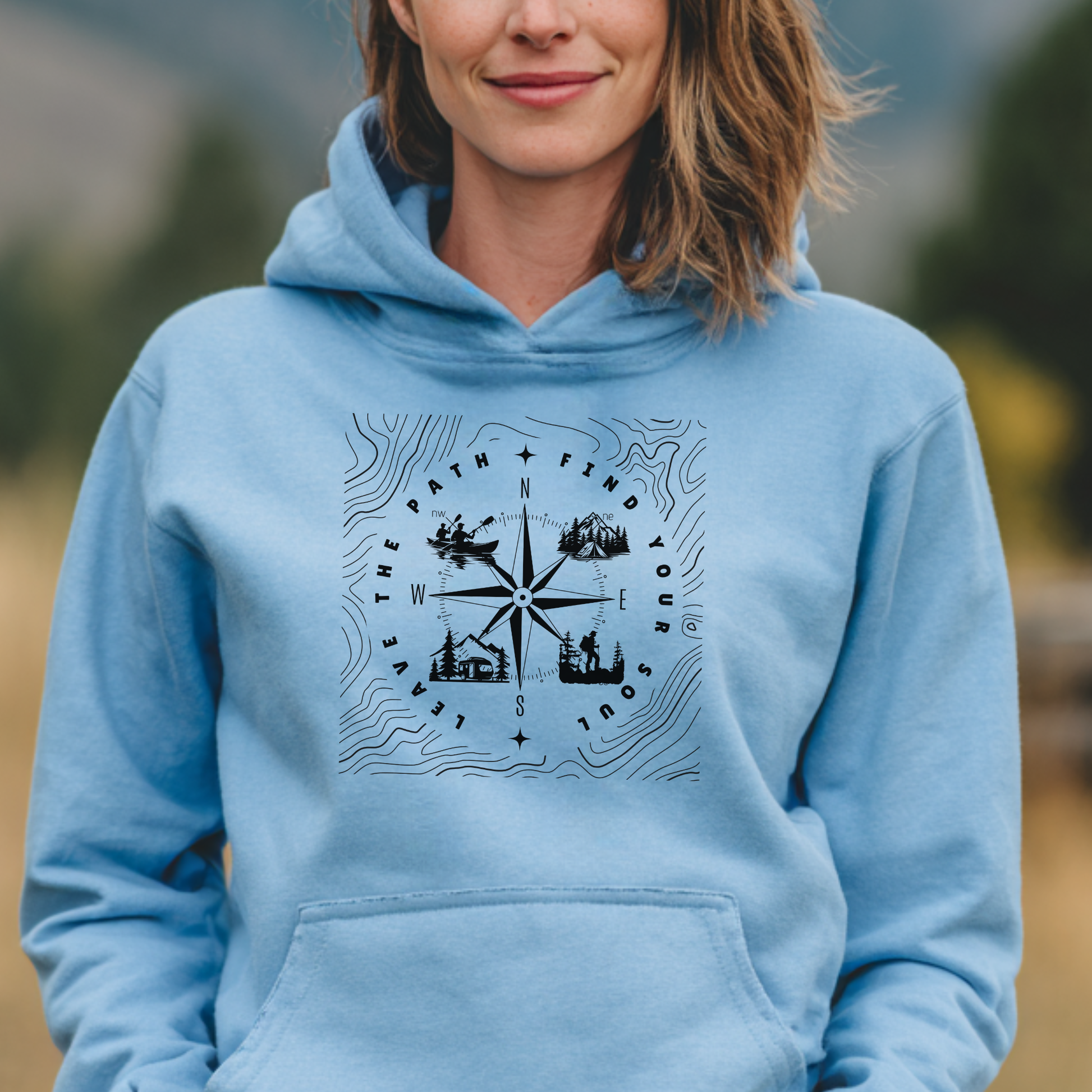 Person wearing a light blue hoodie with a compass design outdoors