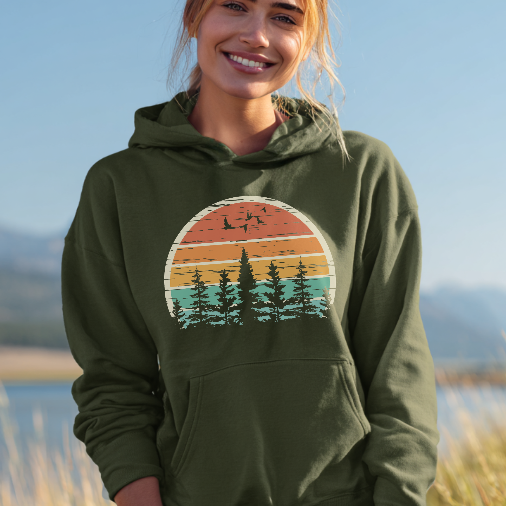 Person wearing a green hoodie with a nature graphic, standing outdoors with a scenic background.