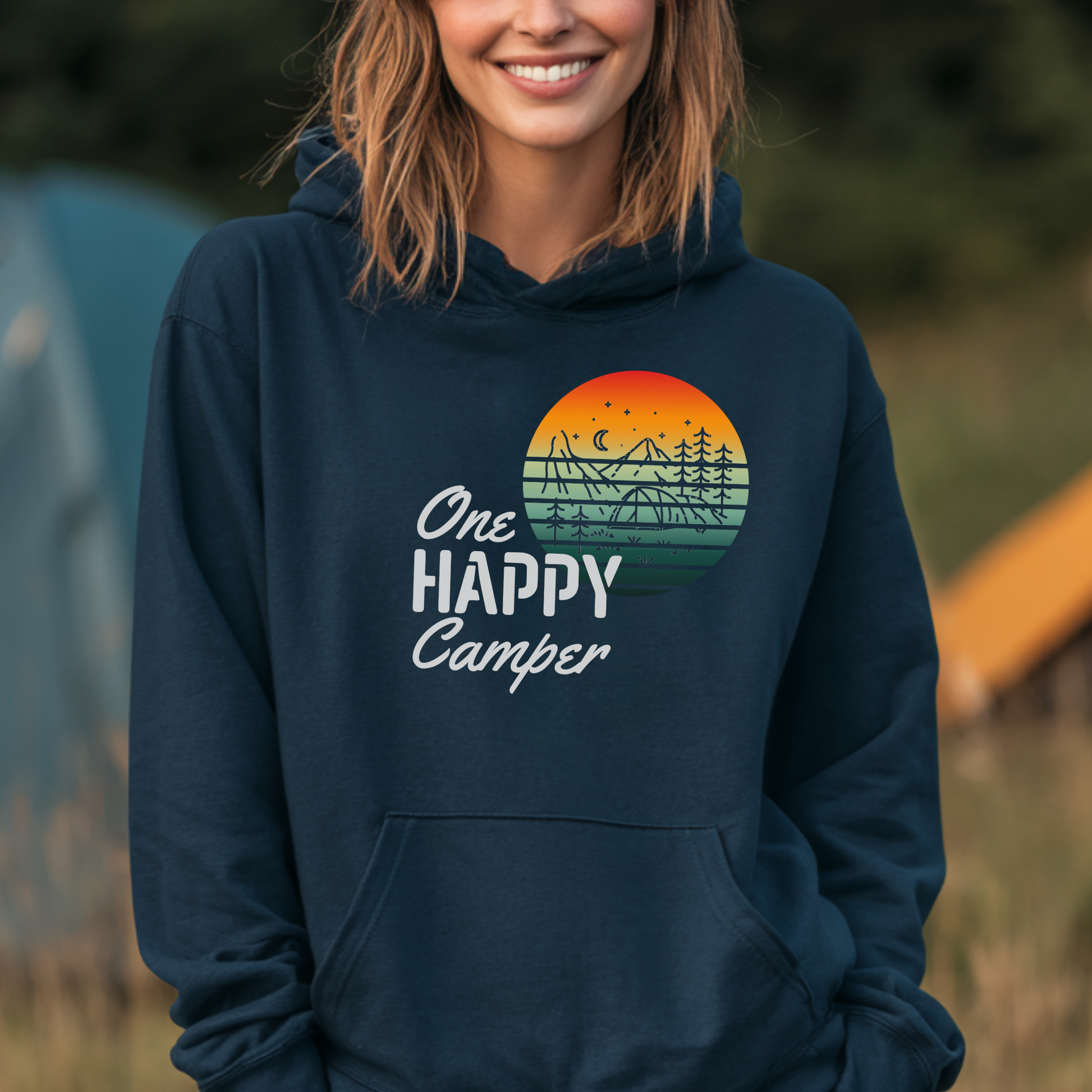 Person wearing a navy hoodie with 'One Happy Camper' design outdoors