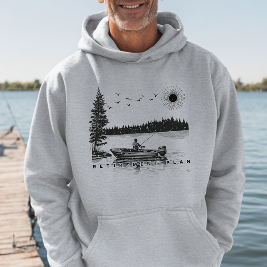 Person wearing a hoodie with a lake and boat design by a body of water