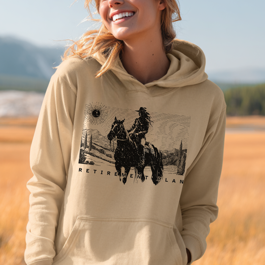 Person wearing a beige hoodie with a graphic design of a person on a horse and text 'Retirement Plan' in a field.