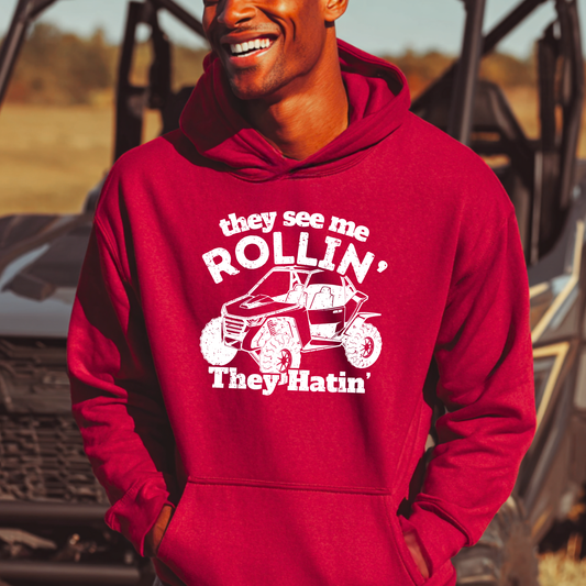 Person wearing a red hoodie with text and graphic design, standing in front of a vehicle.