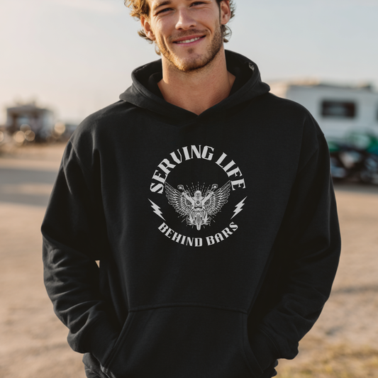 Man wearing a black hoodie with a graphic design and text, standing outdoors.