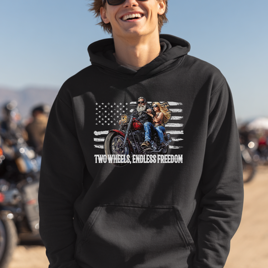 Person wearing a black hoodie with a graphic design and text, standing in a desert-like setting with motorcycles.