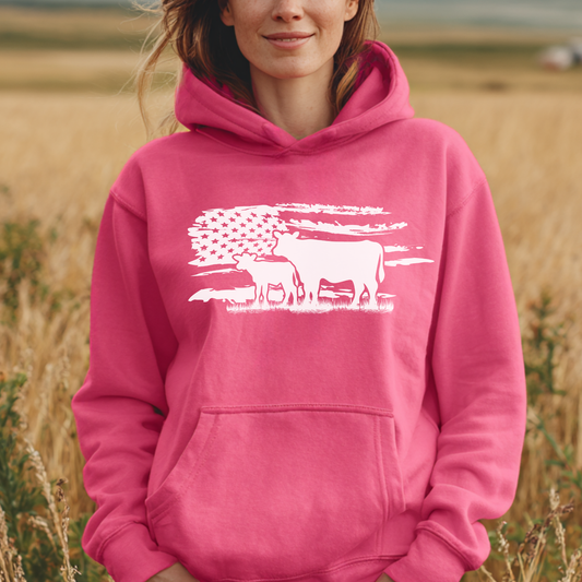 Person wearing a pink hoodie with a white graphic design in a field
