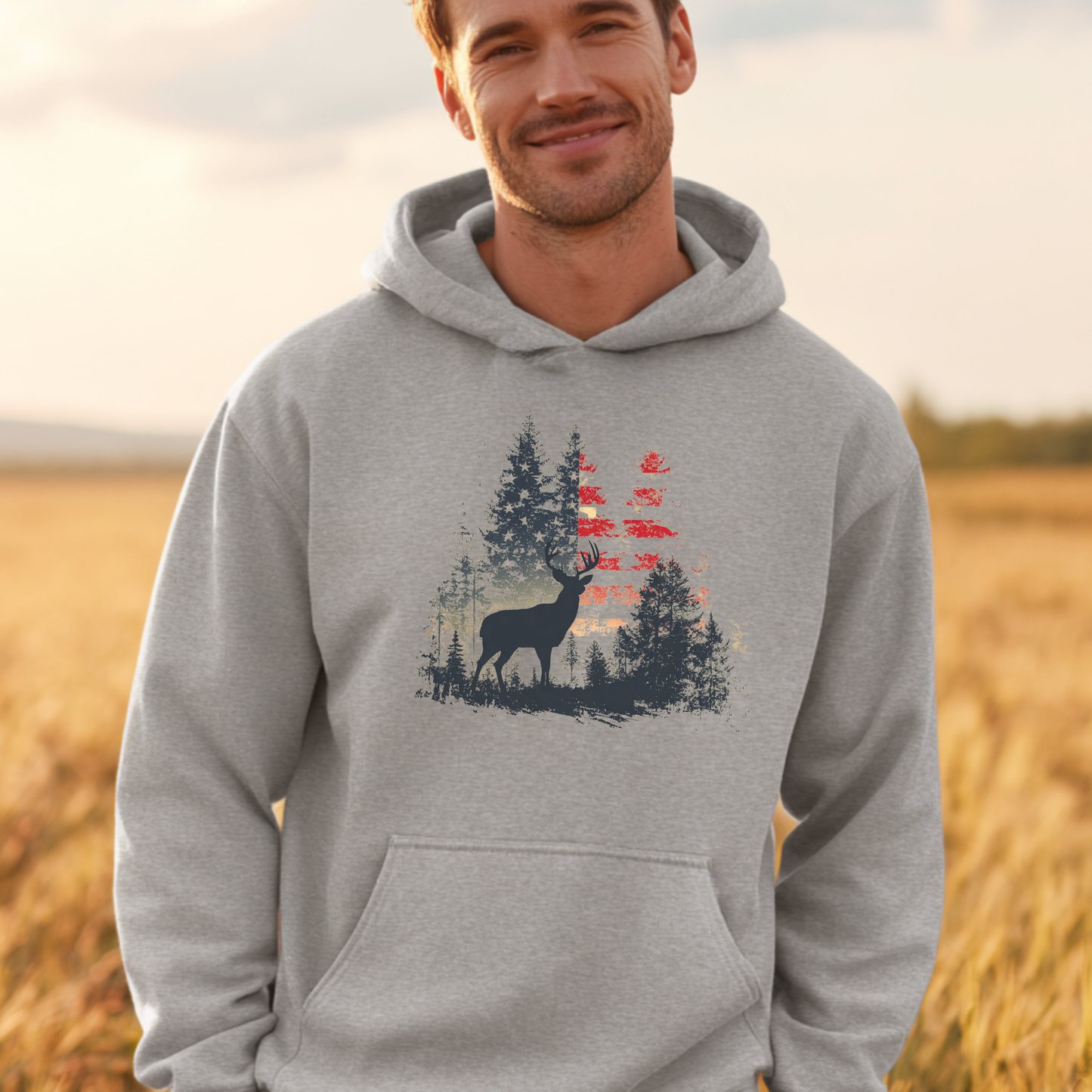 Man wearing a gray hoodie with a nature-themed design in a field