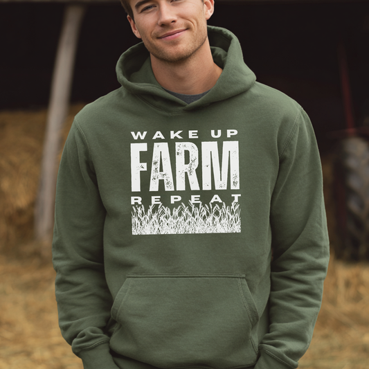 Man wearing a green hoodie with 'Wake Up, Farm, Repeat' text in a barn setting