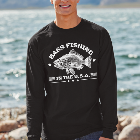 Person wearing a black long-sleeve shirt with 'Bass Fishing in the U.S.A.' graphic by a body of water.