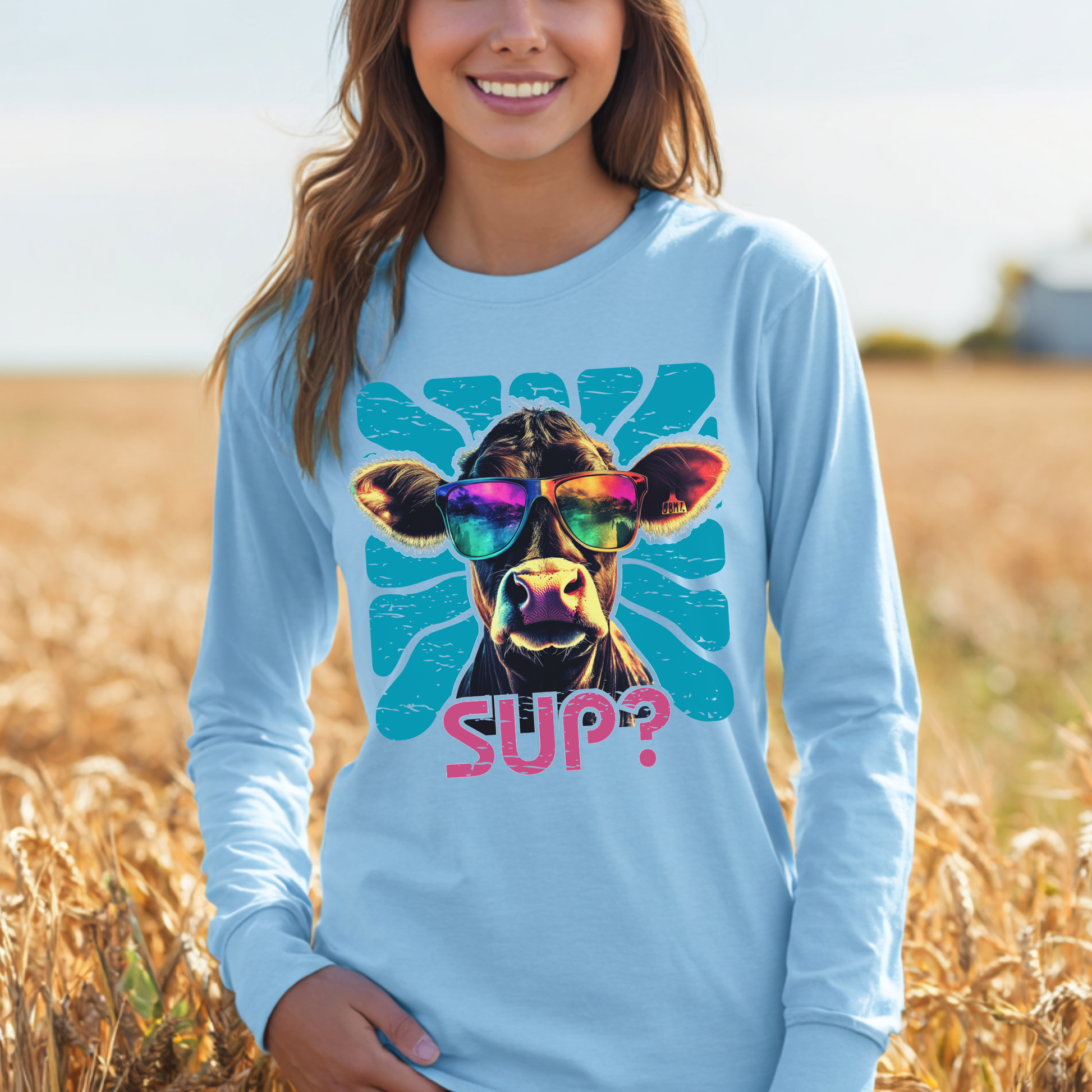 Person wearing a light blue long-sleeve shirt with a colorful cow graphic and 'SUP?' text in a field.