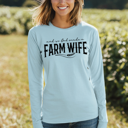 Woman wearing a light blue long-sleeve shirt with 'Farm Wife' text in a field.