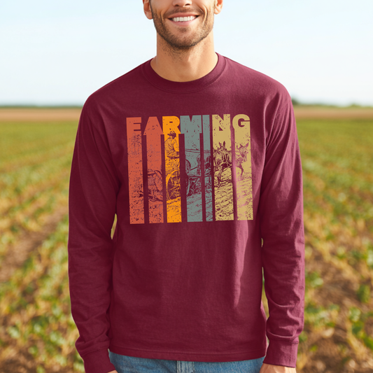 Man wearing a maroon long-sleeve shirt with 'Farming' graphic in a field