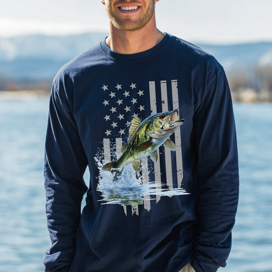 Man wearing a navy blue long-sleeve shirt with a fish and American flag design, standing by a body of water.